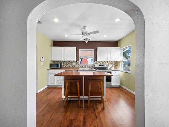 kitchen with wood counters, stainless steel appliances, and white cabinetry