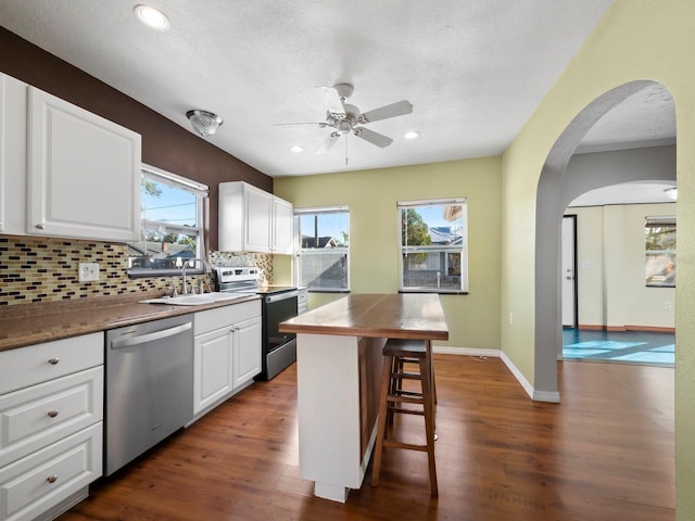 kitchen with white cabinets, appliances with stainless steel finishes, a breakfast bar, and sink