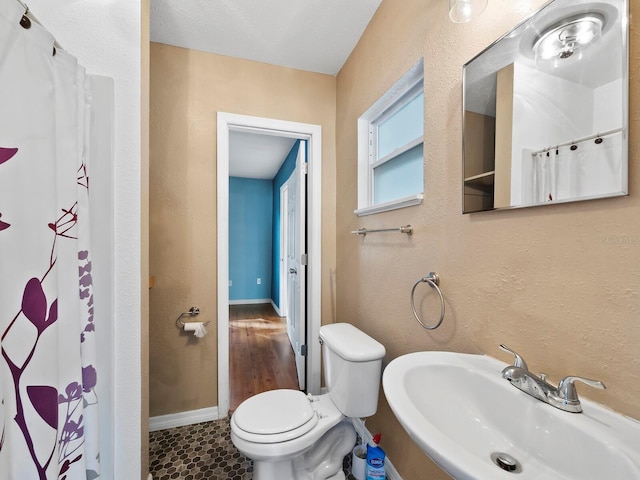 bathroom with walk in shower, sink, and toilet