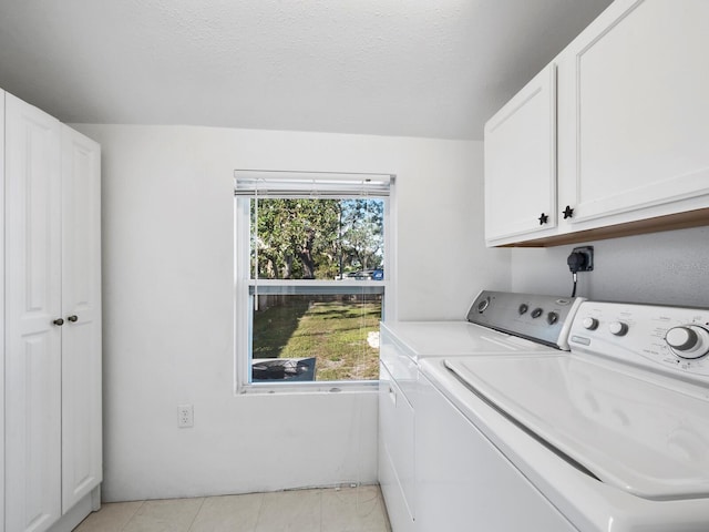 washroom featuring cabinets, plenty of natural light, and washer and dryer