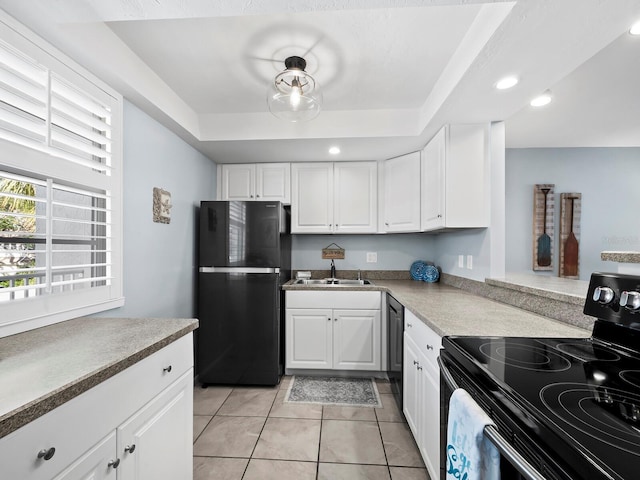 kitchen with white cabinets, sink, a tray ceiling, and black appliances