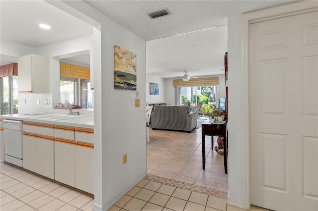 kitchen with ceiling fan, sink, light tile patterned flooring, white dishwasher, and white cabinets