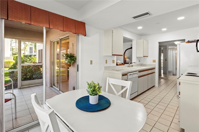 kitchen featuring white cabinets, light tile patterned floors, white appliances, and sink