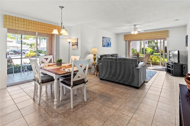 dining area featuring ceiling fan with notable chandelier, light tile patterned floors, and a textured ceiling