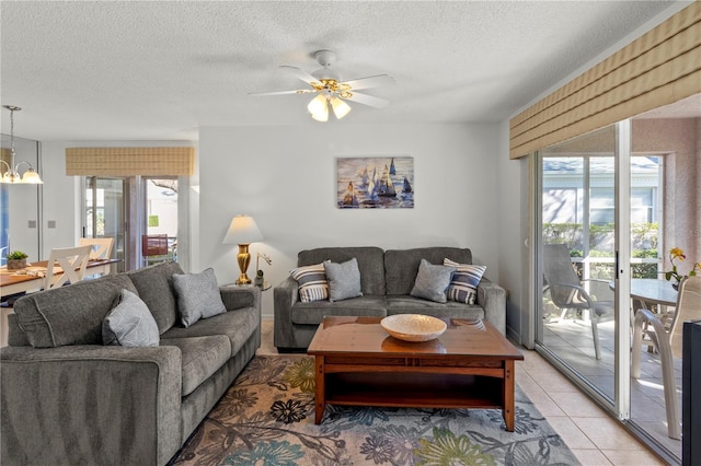 living room featuring a textured ceiling, light tile patterned floors, and ceiling fan with notable chandelier