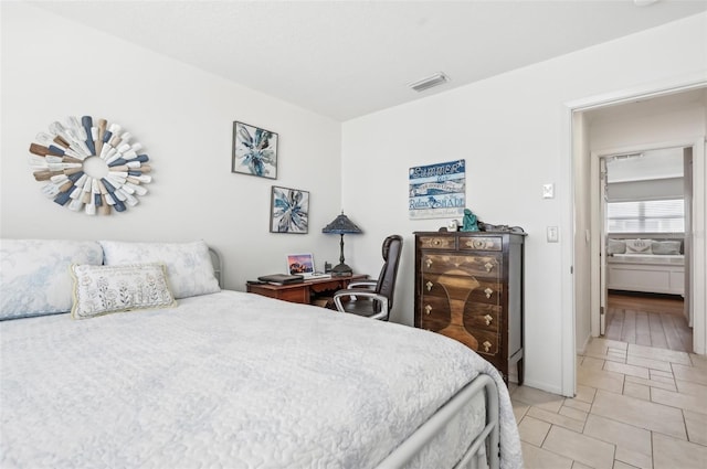 bedroom with ensuite bath and light tile patterned flooring