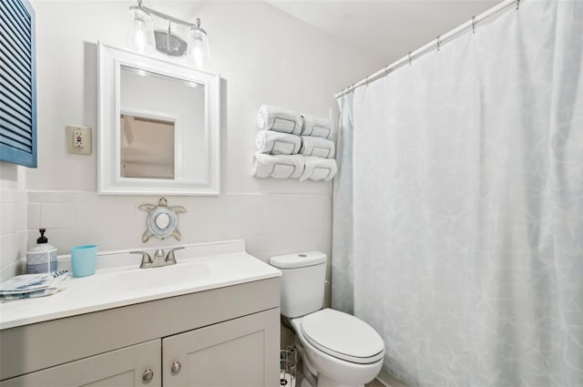 bathroom with vanity, toilet, and tile walls