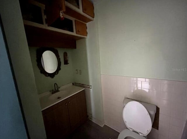 bathroom featuring vanity, tile walls, and toilet