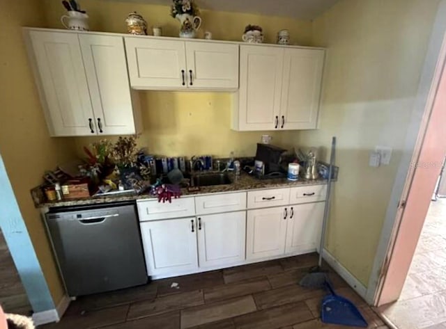 kitchen with stainless steel dishwasher, dark stone countertops, and white cabinetry