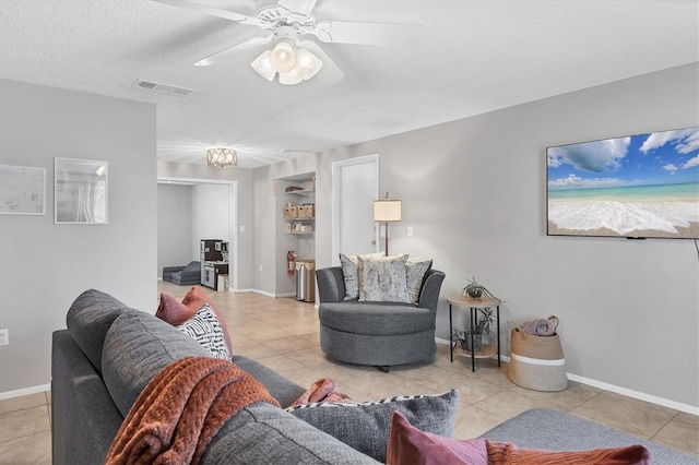 living room with ceiling fan, light tile patterned floors, and a textured ceiling