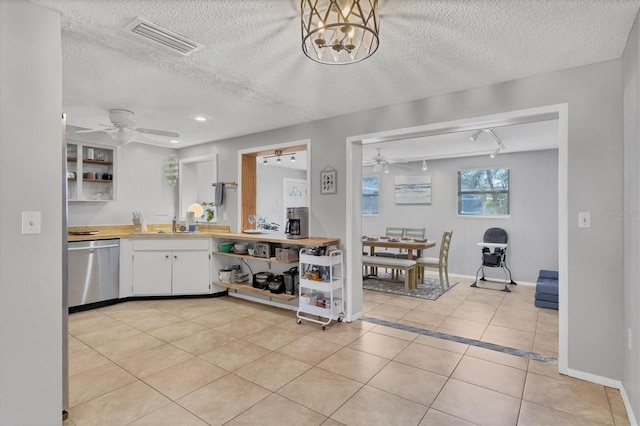 kitchen featuring stainless steel dishwasher, a textured ceiling, ceiling fan, white cabinets, and light tile patterned flooring