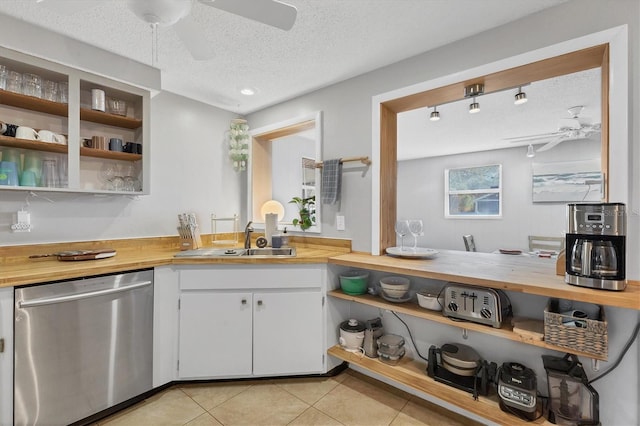 kitchen with stainless steel dishwasher, wood counters, and white cabinets