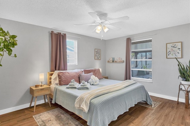 bedroom featuring hardwood / wood-style floors, ceiling fan, and a textured ceiling