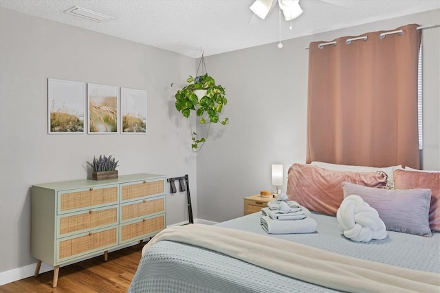 bedroom featuring hardwood / wood-style flooring, ceiling fan, and a textured ceiling