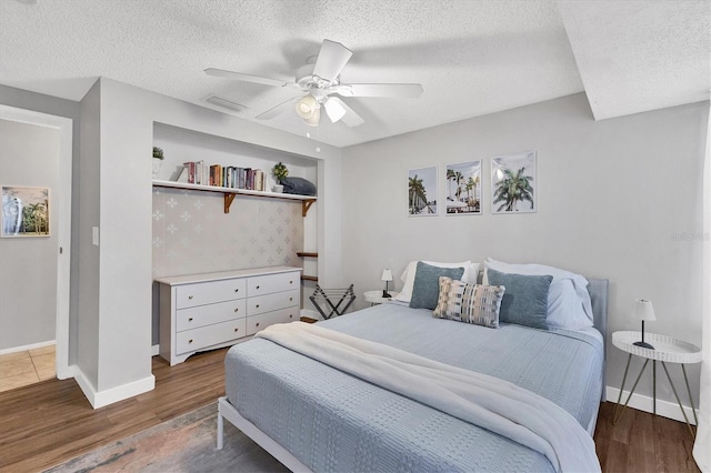 bedroom with ceiling fan, dark wood-type flooring, and a textured ceiling