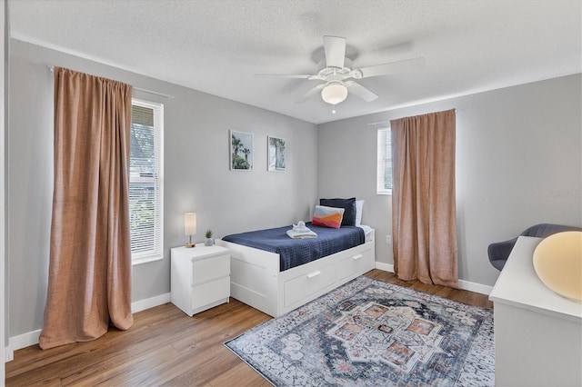 bedroom with ceiling fan, sink, light hardwood / wood-style flooring, and multiple windows