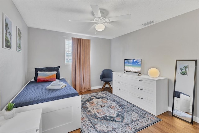 bedroom featuring ceiling fan, light wood-type flooring, and a textured ceiling