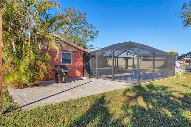 rear view of property featuring a yard, a patio, and glass enclosure