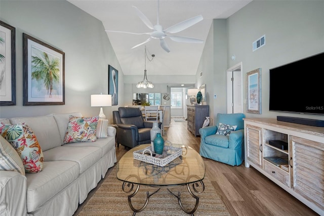 living room featuring hardwood / wood-style floors, high vaulted ceiling, and ceiling fan with notable chandelier