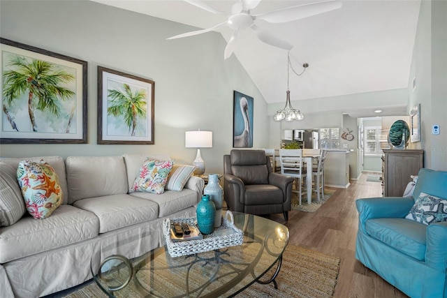 living room with lofted ceiling, ceiling fan with notable chandelier, and dark hardwood / wood-style floors