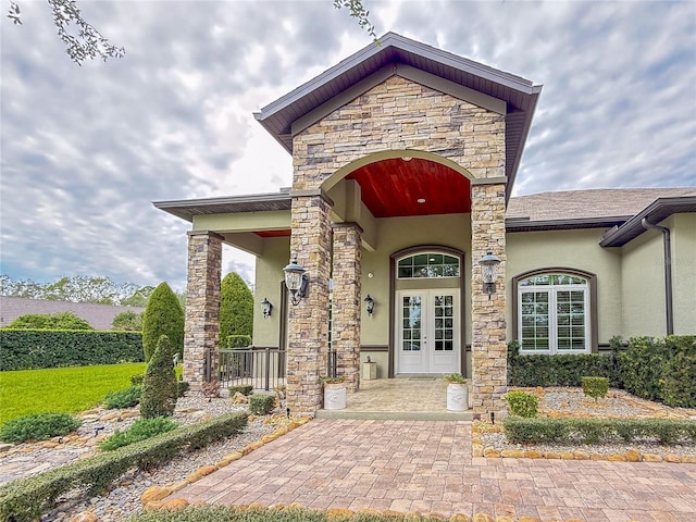 view of exterior entry featuring french doors and a porch