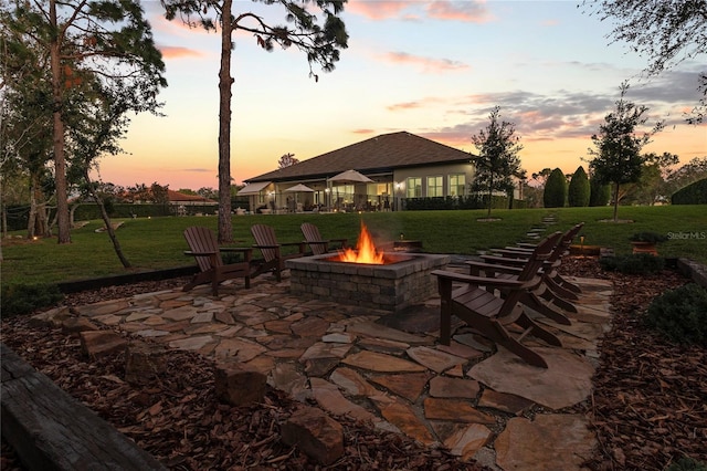 patio terrace at dusk featuring a yard and a fire pit