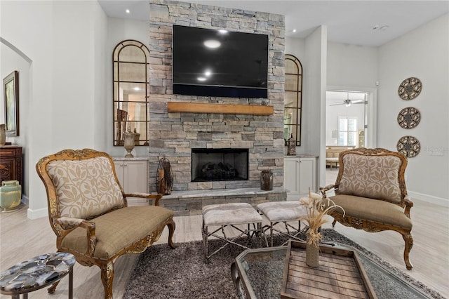 living room featuring hardwood / wood-style floors, ceiling fan, and a fireplace