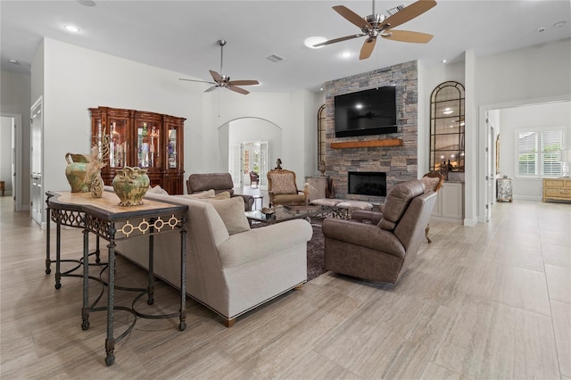 living room featuring a stone fireplace and ceiling fan