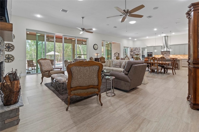 living room with a stone fireplace and ceiling fan