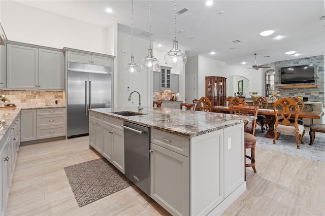 kitchen featuring gray cabinetry, sink, ceiling fan, an island with sink, and stainless steel appliances