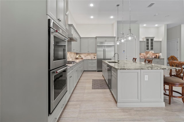 kitchen with a large island, hanging light fixtures, a kitchen bar, decorative backsplash, and appliances with stainless steel finishes