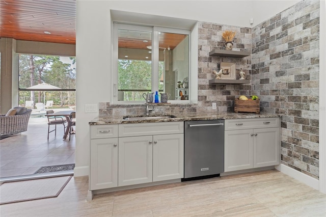 kitchen with stone counters, white cabinetry, and sink