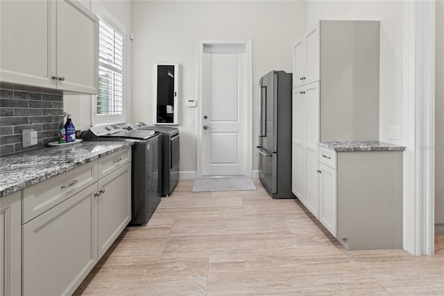 kitchen with white cabinets, light tile patterned flooring, high end fridge, and washing machine and clothes dryer