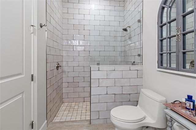 bathroom with tiled shower and toilet