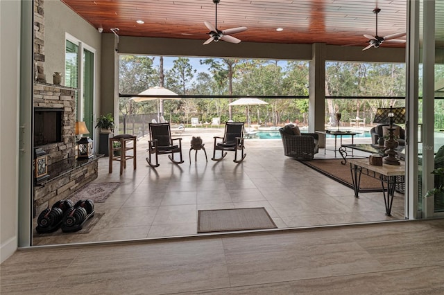 sunroom / solarium with ceiling fan, plenty of natural light, and wood ceiling