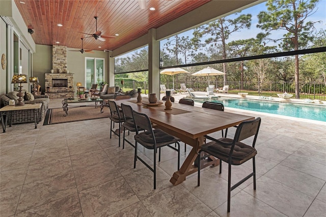 view of patio / terrace featuring a fenced in pool, ceiling fan, and a fireplace