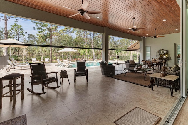 sunroom featuring ceiling fan, a swimming pool, and wooden ceiling