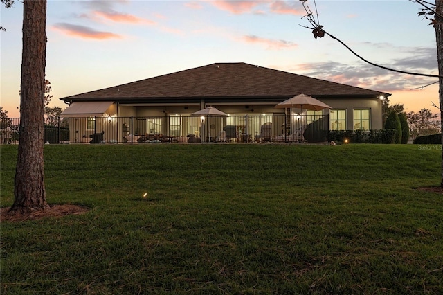 back house at dusk featuring a yard