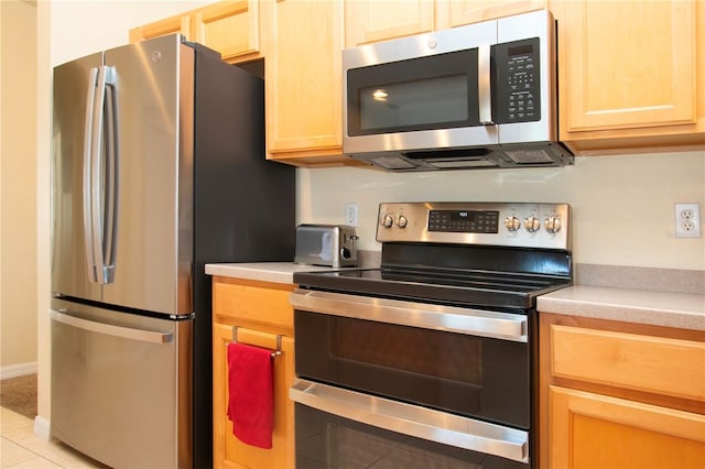 kitchen with light brown cabinets, light tile patterned floors, and stainless steel appliances