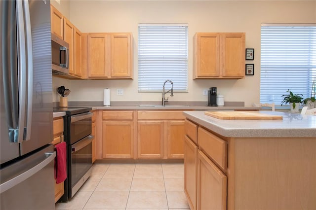 kitchen with sink, light tile patterned floors, stainless steel appliances, and light brown cabinetry