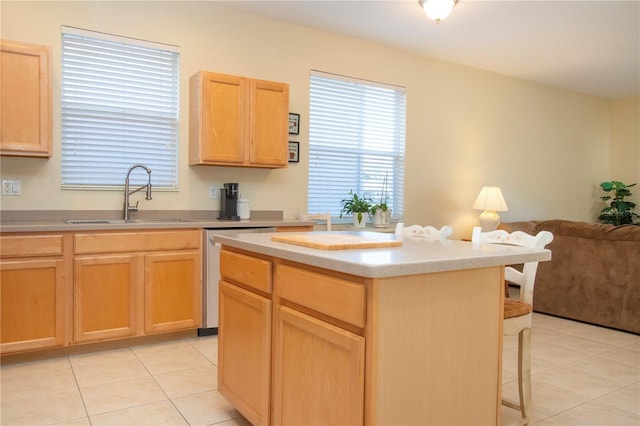 kitchen featuring light brown cabinetry, sink, dishwasher, a kitchen island, and light tile patterned flooring