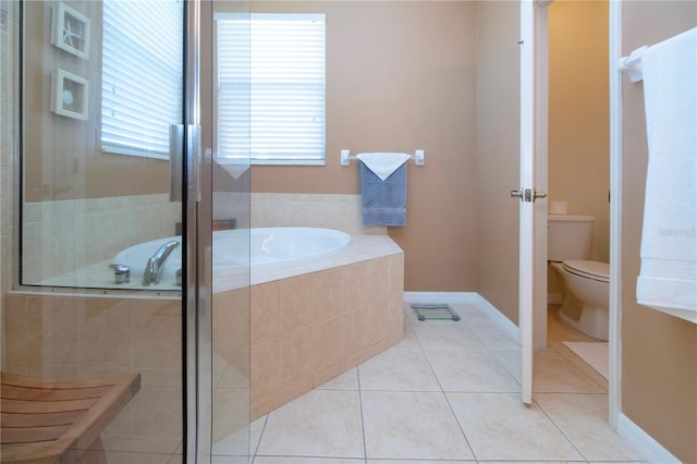 bathroom with tile patterned floors, tiled tub, and toilet