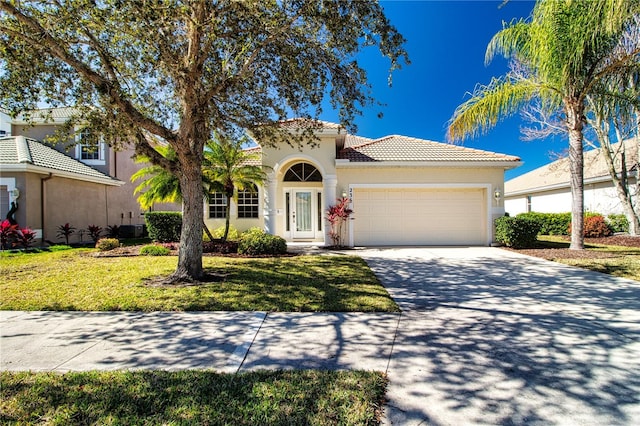 mediterranean / spanish-style house featuring central AC unit, a garage, and a front yard