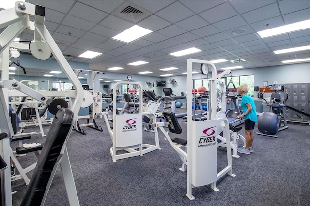 workout area featuring a drop ceiling and dark colored carpet