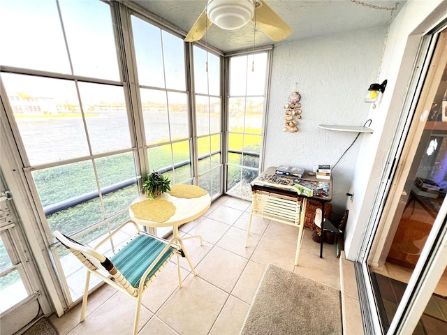 sunroom with a wealth of natural light, a water view, and ceiling fan