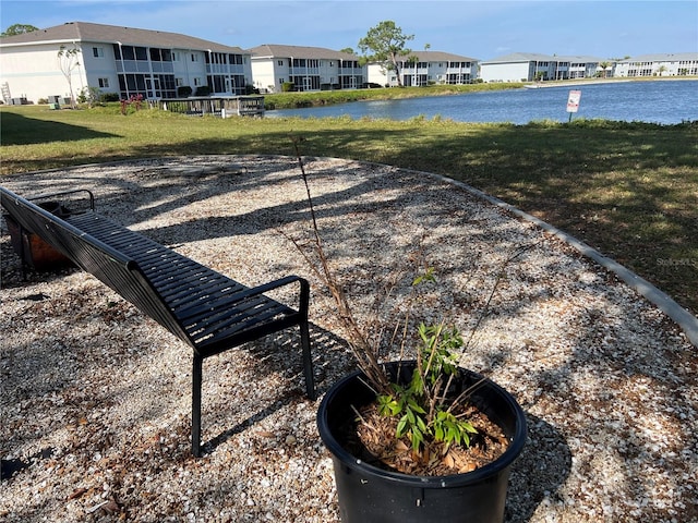 surrounding community with a water view and a yard