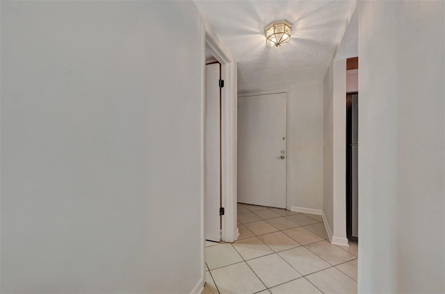 corridor with light tile patterned floors and a textured ceiling