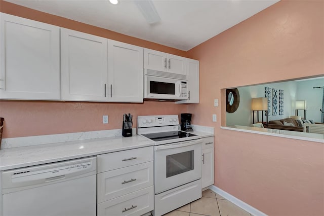 kitchen with white cabinets, light tile patterned floors, white appliances, and light stone countertops