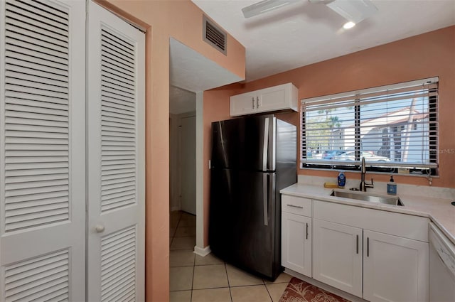 kitchen featuring stainless steel fridge, white dishwasher, sink, light tile patterned floors, and white cabinetry