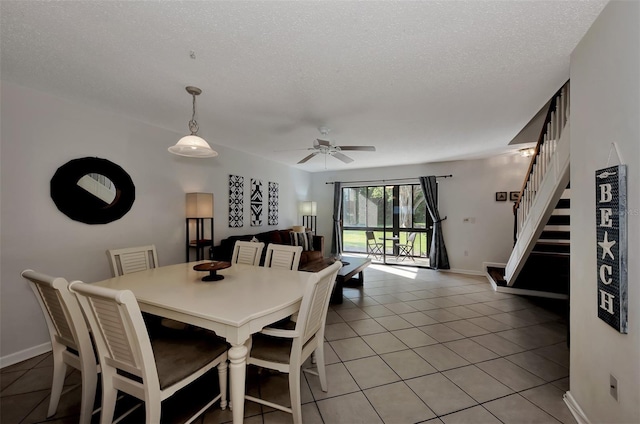 dining space featuring ceiling fan, light tile patterned flooring, and a textured ceiling